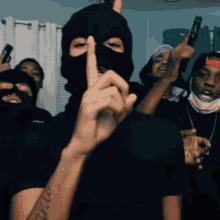 a man in a ski mask holds up his finger