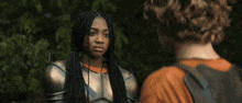 a woman in armor is talking to a man