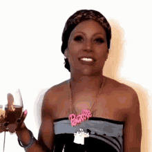 a woman wearing a barbie necklace is holding a wine glass
