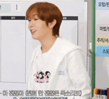 a man wearing a white shirt with three penguins on it is standing in front of a whiteboard .