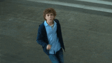a young man in a blue shirt and a blue jacket is running