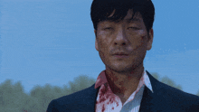 a man in a suit has blood on his face and neck