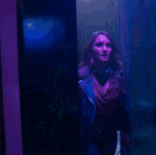 a woman is standing in a dark room with purple lights