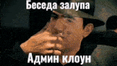 a man in a hat is smoking a cigarette with a caption in russian .