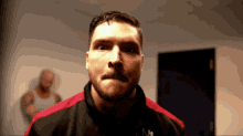 a man with a beard wearing a black and red shirt that says n1 on it
