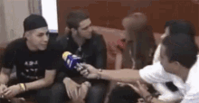 a group of people are sitting on a couch talking to each other .