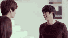 a man in a brown sweater is laughing with another man and a woman