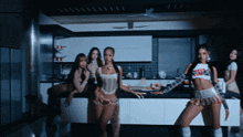 a group of women are standing in a kitchen and one of them is wearing a white top that says ' i love you '