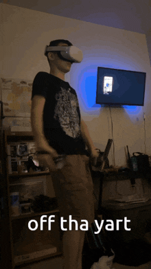 a man wearing a virtual reality headset is holding a controller in front of a television with the caption off the yart