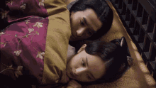 a man and a woman are laying on a bed with a purple blanket