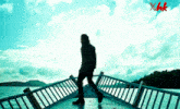 a silhouette of a man walking across a bridge with xhk written on the bottom