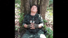 a man in a military uniform is sleeping under a tree with the letter e on his chest