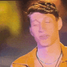 a man wearing a yellow shirt and a necklace is making a funny face .