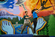 a man and a woman are dancing in front of a mural that says ' aerial ' on it
