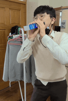 a man wearing glasses and a mask is drinking from a carton that says ' sprite ' on it