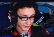 a man wearing glasses and headphones is smiling in front of a computer screen