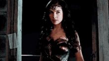 wonder woman is standing in front of a door in a dark room .