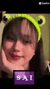 a girl wearing a headband with frog ears and the name sai on the bottom