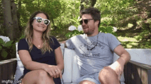 a man wearing a st andrews college shirt sits next to a woman
