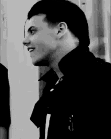 a man in a black jacket is smiling in a black and white photo .