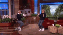 two women are dancing on a stage with the word ellen behind them