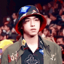 a young man wearing a bucket hat and a green jacket is standing in front of a crowd .