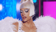 a drag queen is wearing a white feathered dress