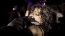 a woman with curly hair is dancing in a crowd at a party