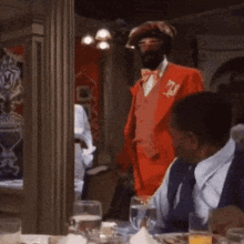 a man in a red suit is standing in a room