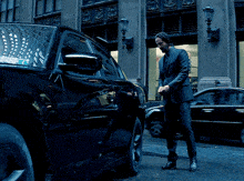 a man in a suit walks towards a car
