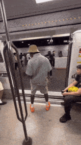a man wearing a hat is standing in the doorway of a subway car