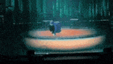 a person in a blue jacket is standing on a stage in front of a circular light