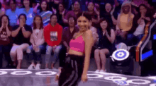 a woman is dancing in front of a crowd of people sitting in a stadium .