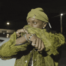 a woman wearing a green fur coat and a green beanie