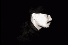 a man with a mustache is standing in the dark and the words come para penda t are visible