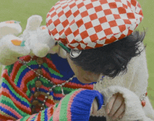 a person wearing a colorful sweater and a red and white checkered hat