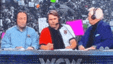 three men wearing headphones are sitting at a podium talking to each other .