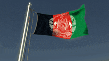 the flag of afghanistan is flying in the wind against a blue sky