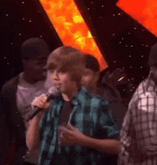 a young boy singing into a microphone in front of a crowd