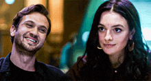 a man and a woman are smiling at each other and looking at the camera