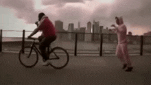a man is riding a bike while a woman stands behind him