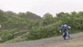 a person in a robot costume is running down a dirt road with trees in the background .