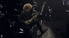 a man playing a guitar on a stage with the letter d visible