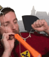 a man wearing headphones and a red shirt with a ferrari logo on it is blowing a balloon