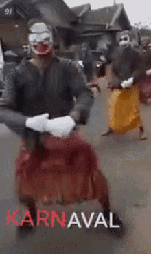 a man wearing a clown mask is dancing in a parade with the word karnaval in red
