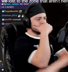 a man wearing headphones is sitting in front of a microphone with his hand on his face .