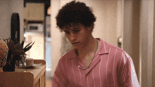 a man in a pink striped shirt is standing in a room