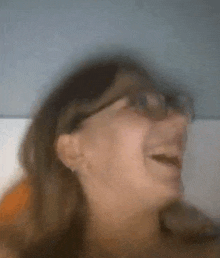 a woman wearing glasses is laughing and making a funny face .