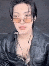 a young man wearing sunglasses and a leather jacket is talking on a video call .