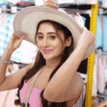 a woman wearing a pink top and a white hat is smiling for the camera .